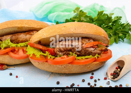 Sandwich: rotoli di carne con verdure in un panino con pomodoro e foglie di lattuga. Foto Stock