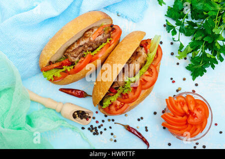 Sandwich: rotoli di carne con verdure in un panino con pomodoro e foglie di lattuga. Vista superiore Foto Stock