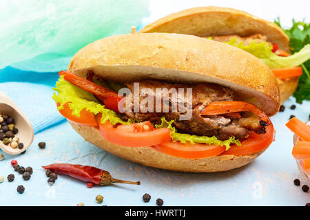 Sandwich: rotoli di carne con verdure in un panino con pomodoro e foglie di lattuga. Foto Stock