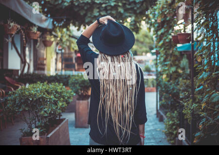 Vista posteriore della donna con dreadlocks in piedi dal recinto nel parco Foto Stock
