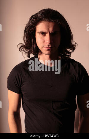 Brutale man in black con capelli lunghi. Foto Stock