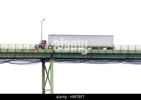 Un semi-carrello attraversa un alto ponte di fronte a un vuoto cielo bianco con un sacco di spazio di copia Foto Stock