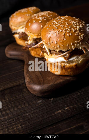 In casa Mini Hamburger di manzo con insalata Coleslaw sul piccolo tagliere di legno. Carne alla Brace panini sul tavolo rustico. Foto Stock