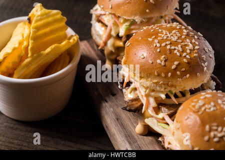 In casa Mini Hamburger di manzo con insalata Coleslaw sul piccolo tagliere di legno. Carne alla Brace panini sul tavolo rustico. Foto Stock