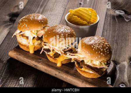 In casa Mini Hamburger di manzo con insalata Coleslaw sul piccolo tagliere di legno. Carne alla Brace panini sul tavolo rustico. Foto Stock