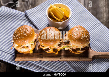 In casa Mini Hamburger di manzo con insalata Coleslaw sul piccolo tagliere di legno. Carne alla Brace panini sul tavolo rustico. Foto Stock
