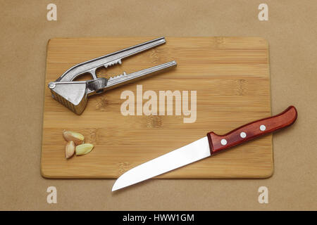 Coltello da cucina con aglio e premere sul bordo di taglio. Foto Stock