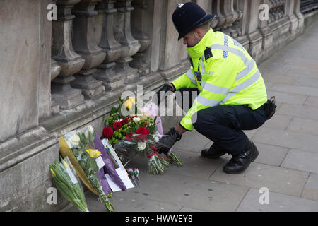 Londra, Regno Unito. 23 Mar, 2017. Un poliziotto getta fiori portato dal pubblico di Whitehall a seguito ieri in un attacco in cui un funzionario di polizia è stato ucciso. Credito: Thabo Jaiyesimi/Alamy Live News Foto Stock