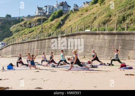 Le donne a praticare yoga sulla spiaggia di Tynemouth su una mattina di sole. Foto Stock