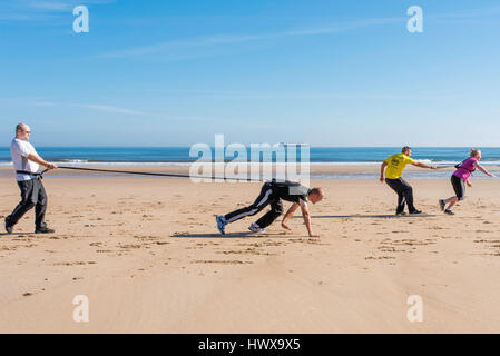 Quattro persone di esercitare nella mattina di sole sulla spiaggia di Tynemouth in Inghilterra settentrionale. Foto Stock