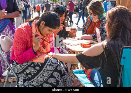 Asin donne pittura henna sulle mani di bianco le donne nel centro cittadino di Newcastle. Foto Stock