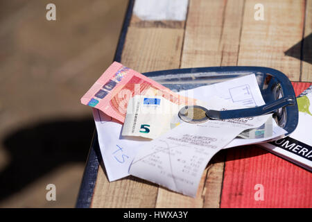 Un conto del bar/cibo a pagamento è stato lasciato su un piatto da portata con una ricevuta sul tavolo del ristorante. Il cliente ha pagato in euro e ha lasciato una mancia Foto Stock