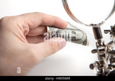 Ispettore delle finanze. Controlla i soldi per autenticità attraverso una lente di ingrandimento. Le mani di close-up. Foto Stock