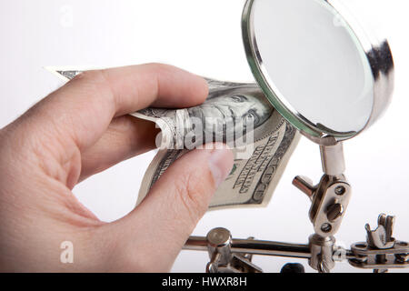 Ispettore delle finanze. Controlla i soldi per autenticità attraverso una lente di ingrandimento. Le mani di close-up. Foto Stock