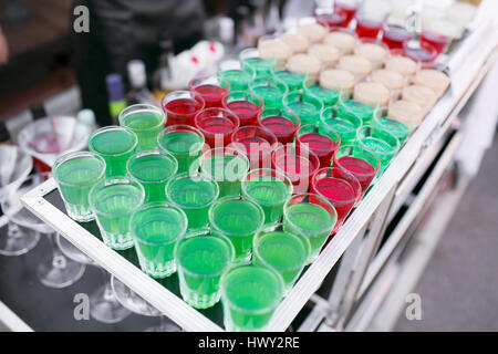 Varietà di colorati di rosso verde e bianco Alcole bellissimo sparatutto dolci scatti cocktail bevanda fresca in piccoli bicchieri in piedi in fila sulla barra mobile Foto Stock