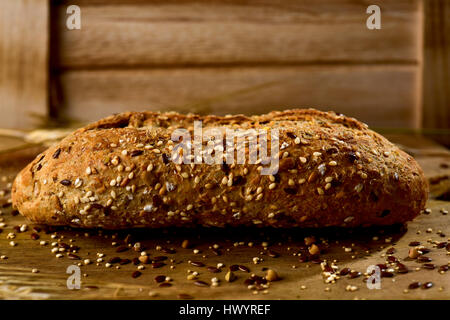 Primo piano di un pane integrale roll e rabboccato con diversi semi come il sesamo e semi di papavero, su una tavola in legno rustico Foto Stock