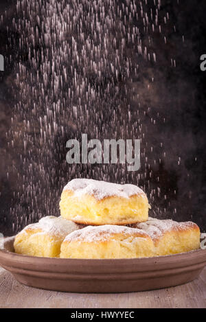 Foto verticale con cinque porzioni di tradizionali dolci fatti in casa riempiti da dolci di ricotta. I dolci sono collocati su argilla marrone piastra e coperti da powde Foto Stock