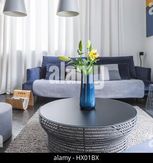 Round tavolino in soggiorno con grande divano e lampade pendenti Foto Stock