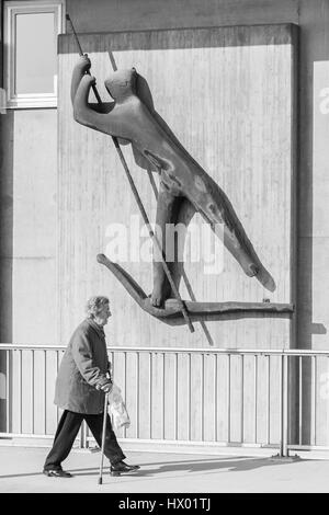 Germania, Regensburg, Marzo 17, 2017, Street la fotografia di una donna anziana sotto un traghettatore di anime di una scultura in Regensburg Foto Stock