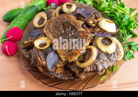 Bistecca di carne di maiale, grigliate con anelli di cipolla e verdure fresche, erbe aromatiche Foto Stock