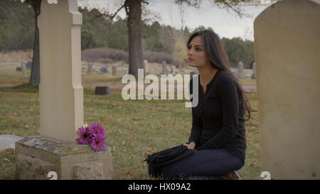 Triste pensieroso donna seduta alla tomba nel cimitero di Solitario Foto Stock