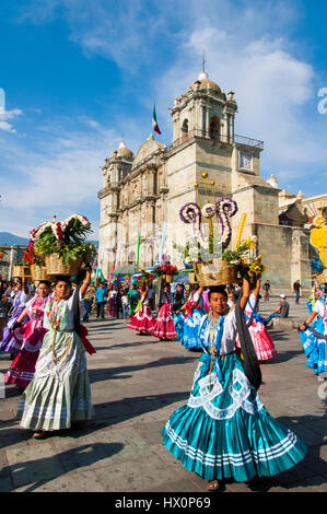 Le donne in abiti tradizionali con cesti di fiori ballare nella principale piazza Zocalo di fronte alla chiesa di Santo Domingo de Guzman Foto Stock