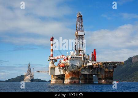 Offshore di fronte montagne verdi con un cielo blu sopra. Foto Stock