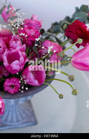 Rosa ranuncoli e tulipani rosa disposizione in vaso di ferro su sfondo chiaro Foto Stock