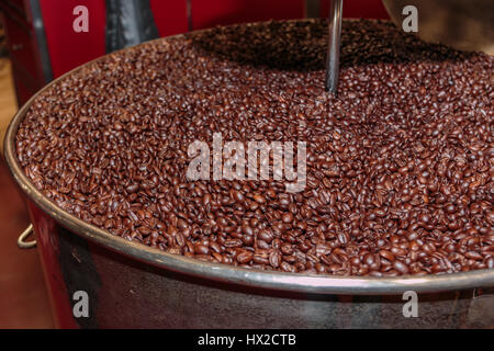 I chicchi di caffè in lavorazione nella macchina di torrefazione Foto Stock