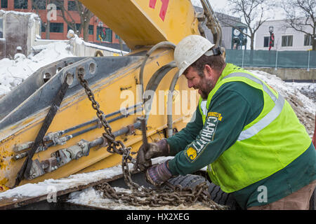 Mt. Clemens, Michigan - un lavoratore per Homrich, una demolizione contraente, prepara attrezzature pesanti per il trasporto presso il sito di un garage per il parcheggio demoliti Foto Stock