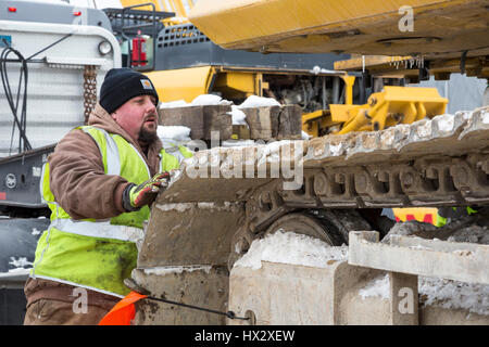 Mt. Clemens, Michigan - un lavoratore per Homrich, una demolizione contraente, prepara attrezzature pesanti per il trasporto presso il sito di un garage per il parcheggio demoliti Foto Stock