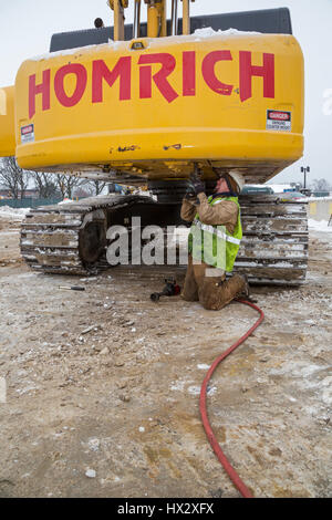 Mt. Clemens, Michigan - un lavoratore per Homrich, una demolizione contraente, prepara attrezzature pesanti per il trasporto presso il sito di un garage per il parcheggio demoliti Foto Stock