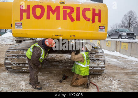 Mt. Clemens, Michigan - Lavoratori per Homrich, una demolizione contraente, preparare attrezzature pesanti per il trasporto presso il sito di un garage per il parcheggio demolizione Foto Stock