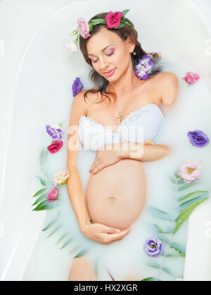 Bella donna incinta nel bagno di latte Foto Stock