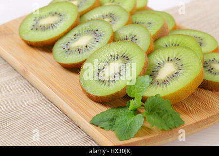 Fette di kiwi maturi disposti sul tagliere di legno - close up Foto Stock