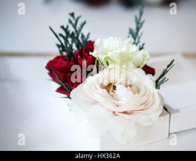 Coppia di anelli di nozze giacente sul rosebud. Foto Stock