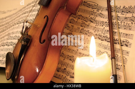 Violino e archetto con foglio di musica e candela Foto Stock