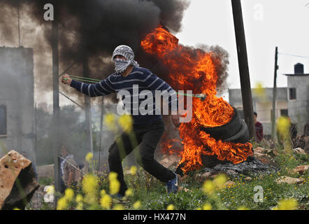 Nablus, Palestina. Il 24 marzo 2017. Un manifestante palestinese scaglia pietre contro soldati israeliani durante scontri dopo una manifestazione di protesta contro l'espansione degli insediamenti ebraici in Kufr Qadoom villaggio vicino alla Cisgiordania città di Nablus, il 24 marzo 2017. Foto Stock