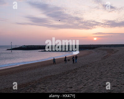 Westbay, Dorset, Regno Unito. Il 24 marzo 2017. La gente sulla spiaggia come il cloud infine si cancella e un vago ma colorato tramonto segue. Con un meteo alto insieme a seguire e temperature più calde previsto per questo fine settimana. © Dan Tucker/Alamy Live News Foto Stock