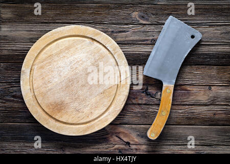 Vecchia mannaia di carne o coltello da prosciutto e round tagliere di legno. Vista da sopra con lo spazio di copia Foto Stock