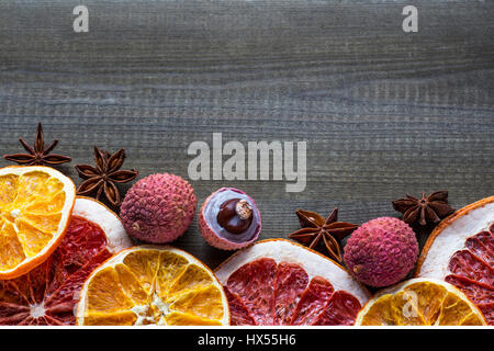 Il Lychee frutti con le fette di agrumi e spezie a stella su sfondo di legno Foto Stock