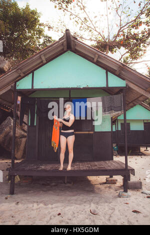 Donna vestiti appesi ad asciugare fuori bungalow sulla spiaggia in Thailandia. Foto Stock