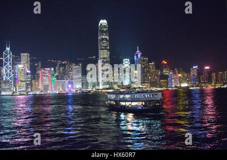 Un traghetto Star attraversa da Wan Chai e sta per dock a Kowloon. Le luci della Central Hong Kong riflettono in acqua durante la notte Foto Stock