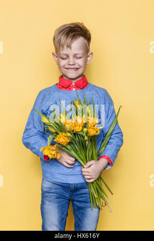 Poco bel bambino con un bouquet di tulipani. Figlio dà la mamma fiori in occasione della Giornata della donna, Giornata della madre. Compleanno. Il giorno di San Valentino. Molla. Foto Stock