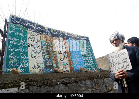 Anantnag, India. 25 Mar, 2017. Un uomo con un cartellone di 'Lettura di riaprire il fake Pathribal incontro caso' in prossimità di un bordo visualizza i nomi delle vittime di Pathribal e massacri Brakpora quando cinque persone uccise nella fase incontro gestito dall esercito e il successivo abbattimento di otto manifestanti nel villaggio Brakpora dalla polizia e CRPF. Credito: Muneeb Ul Islam/Pacific Press/Alamy Live News Foto Stock