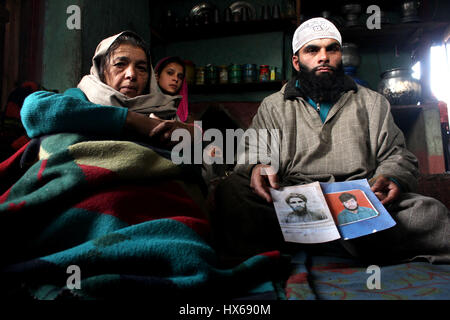 Anantnag, India. 25 Mar, 2017. Rashid Khan figlio e sua madre Zooni una delle vittime e un testimone chiave nel caso tenendo le foto di suo padre e suo fratello il 17 anniversario di uccisioni, la vittima le famiglie organizzando un ricordo si incontrano a Brari-Aangan villaggio di Shangus in questo Sud Kashmir distretto per ricordare cinque persone uccise nella fase incontro gestito dall esercito e il successivo abbattimento di otto manifestanti nel villaggio Brakpora dalla polizia e CRPF. Credito: Muneeb Ul Islam/Pacific Press/Alamy Live News Foto Stock