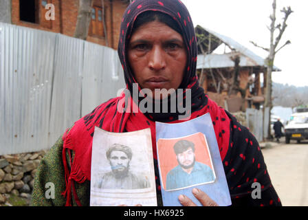 Anantnag, India. 25 Mar, 2017. Naseem, il cui padre e fratello sono stati uccisi in pathribal fake incontro, reagisce mentre posa con la fotografia del suo affini al diciassettesimo anniversario di uccisioni, la vittima le famiglie organizzando un ricordo si incontrano a Brari-Aangan villaggio di Shangus in questo Sud Kashmir distretto per ricordare cinque persone uccise nella fase incontro gestito dall esercito e il successivo abbattimento di otto manifestanti nel villaggio Brakpora dalla polizia e CRPF. Credito: Muneeb Ul Islam/Pacific Press/Alamy Live News Foto Stock