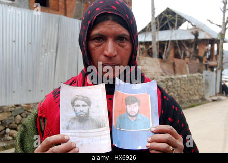 Anantnag, India. 25 Mar, 2017. Naseem, il cui padre e fratello sono stati uccisi in pathribal fake incontro, reagisce mentre posa con la fotografia del suo affini al diciassettesimo anniversario di uccisioni, la vittima le famiglie organizzando un ricordo si incontrano a Brari-Aangan villaggio di Shangus in questo Sud Kashmir distretto per ricordare cinque persone uccise nella fase incontro gestito dall esercito e il successivo abbattimento di otto manifestanti nel villaggio Brakpora dalla polizia e CRPF. Credito: Muneeb Ul Islam/Pacific Press/Alamy Live News Foto Stock