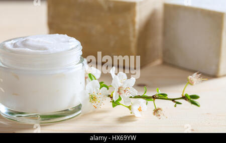 Crema idratante e mandorlo fiorisce su sfondo di legno Foto Stock