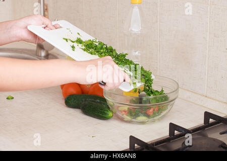 Ragazza taglia un verdi su una scheda su una cucina. Foto Stock